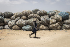 A woman walks past recyclable waste in the Mbeubeuss rubbish dump in Dakar on July 14, 2021. Almost all of it ends up in Mbeubeuss, a landfill about 30 kilometres (18 miles) from the centre which has a notorious reputation as an environmental hazard.