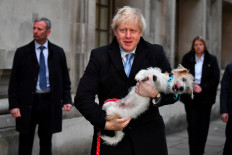 Britain's Prime Minister Boris Johnson holds his dog Dilyn as he leaves a polling station, at the Methodist Central Hall, after voting in the general election in London, Britain, December 12, 2019.