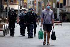 A man walks past police offers patroling the streets of central business district of Sydney on July 31, 2021, as authorities warned against the anti-lockdown protest. 
