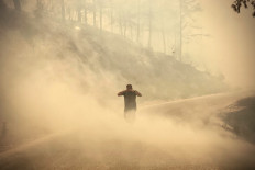 A pedestrian walks through the smoke as a massive wildfire which engulfed a Mediterranean resort region on Turkey's southern coast near the town of Manavgat, on July 30, 2021.