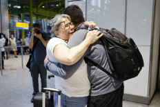 Relatives embrace as they arrive from the United States at Heathrow's Terminal 5 in west London on August 2, 2021 as quarantine restrictions ease.
