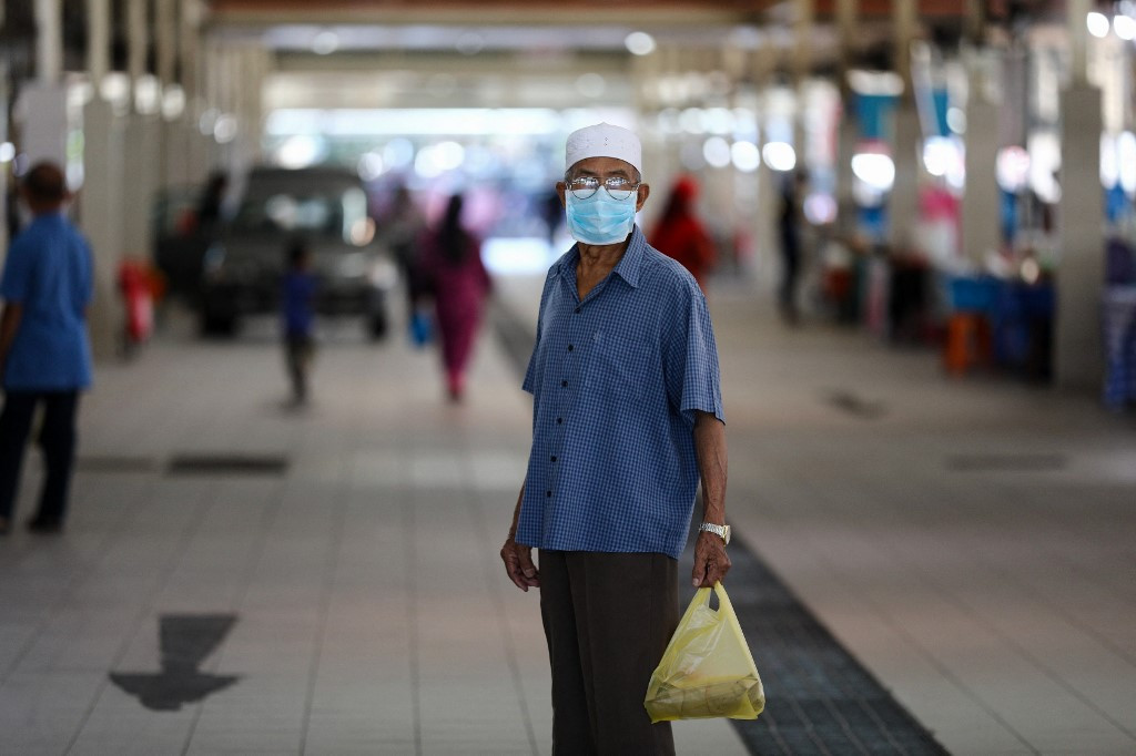A man wearing a face mask, amid concerns over the spread of the COVID-19 coronavirus, holds a plastic bag of goods at the Gadong Night Market in Bandar Seri Begawan on March 16, 2020. 