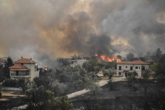 A picture taken on August 6, 2021 shows flames near houses as a fire spreads in the village of Afidnes, some 30 kilometres north of Athens. Hundreds of firefighters battled a blaze on the outskirts of Athens on August 6 as dozens of fires raged in Greece. 