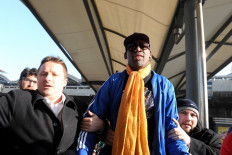 Canadian businessman Michael Spavor (left) walks with former US basketball player Dennis Rodman (center) after arriving from North Korea at Beijing International Airport on January 13, 2014. Rodman returned to China from Pyongyang after a seven-day trip where he sang 