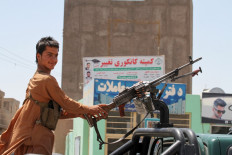 In this picture taken on August 6, 2021, an Afghan militiaman stands on a vehicle keeping a vigil along a road on the outskirts of Herat. 