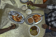 Customers at one of the city's oldest restaurants, Chez Hamdani, enjoy yemenite fish, split fish seasoned and seared in a traditional open-flame clay oven, in Djibouti on April 11, 2021.