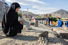 Farzanah Asghari, 18, stands by her sister Rehana's grave in Kabul's Dasht-e-Barchi neighborhood, Afghanistan. Days after losing her younger sister in a bomb attack on the school in Kabul that both girls attended, Farzanah stood by the 15-year-old's grave and quietly wept.