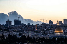 This picture taken from the Mount of Olives shows a general view of Jerusalem's old city with Dome of the Rock mosque in the foreground and a cloud of smoke rising from a large forest fire in the background on August 15, 2021. Residents of several villages on the outskirts of Jerusalem were evacuated Sunday due to a large forest fire, Israeli police said. Firefighters supported by firefighting aircraft were working to put out the blaze, as smoke was visible from much of the city. The fire threatened the villages of Beit Meir, Shoeva and Ramat Raziel, west of Jerusalem, police said in a statement.