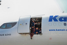 Afghan people climb up on a plane and sit by the door as they wait at the Kabul airport in Kabul on August 16, 2021, after a stunningly swift end to Afghanistan's 20-year war, as thousands of people mobbed the city's airport trying to flee the group's feared hardline brand of Islamist rule. 