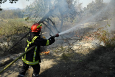 A French firefighter uses a water hose in an attempt to extinguish flames of a forest fire spreading in the area of Var in southern France on August 17, 2021.