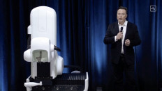 This video grab made from the online Neuralink livestream shows Elon Musk standing next to the surgical robot during his Neuralink presentation on August 28, 2020. Futurist entrepreneur Elon Musk late August 28 demonstrated progress made by his Neuralink startup in meshing brains with computers, saying the work is vital to the future of humanity.