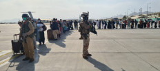This handout picture released and taken by the Italian Defense press office on August 22, 2021 shows soldiers on the tarmac past passengers, who fled Afghanistan, waiting to board on an Italian military aircraft at Kabul airport, to fly to Rome Fiumicino.