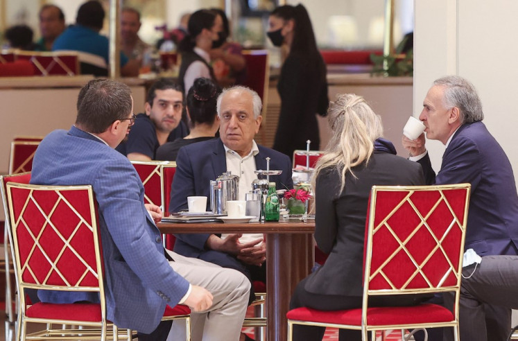 US Special Representative for Afghanistan's Reconciliation Zalmay Khalilzad (center) sits in a coffee shop ahead of a session of the peace talks between the Afghan government and the Taliban in the Qatari capital Doha, on July 17, 2021. 