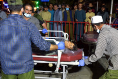 Volunteers and medical staff bring an injured man on a stretcher to a hospital for treatment after two powerful explosions, which killed dozens of people, outside the airport in Kabul on Aug. 26, 2021. 