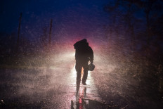 Montegut fire chief Toby Henry walks back to his fire truck in the rain as firefighters cut through trees on the road in Bourg, Louisiana as Hurricane Ida passes on August 29, 2021. Hurricane Ida struck the coast of Louisiana on August 29 as a powerful Category 4 storm, 16 years to the day after deadly Hurricane Katrina devastated the southern US city of New Orleans.