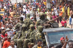 People celebrate in the streets with members of Guinea's armed forces after the arrest of Guinea's president, Alpha Conde, in a coup d'etat in Conakry, September 5, 2021. Guinean special forces seized power in a coup on September 5, arresting the president and imposing an indefinite curfew in the poor west African country. 
