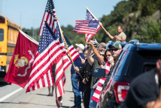 People hold flags while the motorcade carrying fallen Marine Sgt. Johanny Rosario Pichardo passes on I-93 North on September 11, 2021 in Stoneham, Massachusetts. Rosario Pichardo was one of 13 troops killed August 26 in the suicide bomber attack during the evacuation mission at the Kabul airport 
