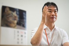 This picture taken on July 30, 2021 by AFPBB News shows immunology professor Toru Miyazaki explaining his study past a copy of his book (L) during an interview with AFPBB News at the University of Tokyo.