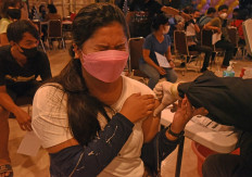 A woman reacts as she receives a COVID-19 jab during a mass vaccination event at the Indonesian Bethel Church in Serang, Banten, West Java, on Friday. The local health agency, the Indonesian Military (TNI) and the National Police organized inoculation drives in places of worship to help the government achieve its COVID-19 vaccination target.
