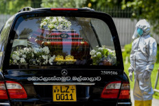 A cemetery worker wearing Personal Protective Equipment (PPE) stand next to a hearse carrying the coffin of Eliyantha White, a local shaman who claimed he had super natural powers to end the pandemic and died of the Covid-19 coronavirus, at the crematorium of the Colombo General Cemetery on September 23, 2021.