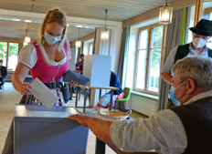 Voters wearing the traditional clothes of the region cast their ballot at a polling station during general elections in Bayrischzell, southern Germany, on September 26, 2021. 
