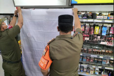 Out of sight: West Jakarta's Public Order Agency (Satpol PP) covers the shelf displaying cigarettes with white fabric in a minimarket chain on Sep. 13, 2021. (Kompas.com/Sonya Teresa)