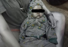Exploited?: A baby covered entirely with silver paint was brought by 'silver humans' to the street to help them make more money (Courtesy of @tangsel_update on Instagram).