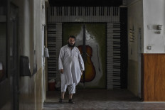 This photo taken on September 14, 2021 shows a member of the Taliban walking in a corridor at the Afghanistan National Institute of Music in Kabul. The Taliban, who banned music outright during their brutal and oppressive rule from 1996 to 2001, have promised a more moderate brand of rule this time -- though they have made clear that they will run Afghanistan within the restrictive limits of their interpretation of sharia law.