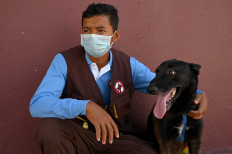 This photo taken on September 27, 2021 shows trainer Khom Sokly sitting with a dog trained to detect the Covid-19 coronavirus after a training session at the Cambodian Mine Action Centre (CMAC) in Kampong Chhnang province.