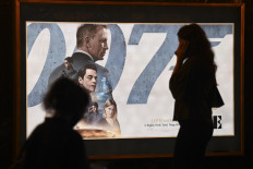 A woman walks past a poster of the latest James Bond movie “No Time to Die” at a PVR cinema in New Delhi on Sept. 30, 2021.