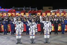 This screen grab made from video taken and released on October 15, 2021 by Chinese state broadcaster CCTV shows astronauts (L-R) Ye Guangfu, Wang Yaping and Zhai Zhigang, the second crew for China's new space station, waving at a departure ceremony before their launch on the Shenzhou 13 spacecraft, at the Jiuquan Satellite Launch Centre in the Gobi desert, in northwest China.