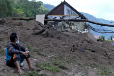 A resident sits near damaged houses at the scene of a landslide triggered by a 4.8-magnitude earthquake in Trunyan village, Bangli, Bali, on Saturday.