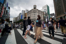 Pedestrians cross a street in Tokyo's shopping district of Ginza on June 27, 2021.