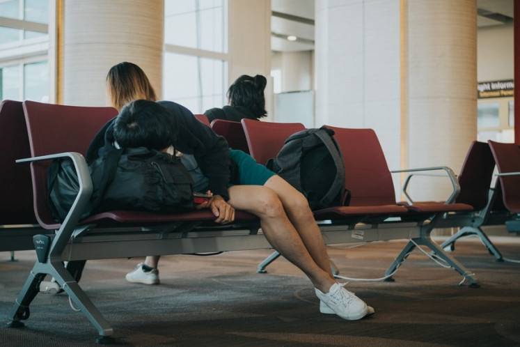 Long flight: Tourist sleeping at the Bali airport. (Unsplash/Joyce Romero)