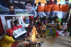 Cricket fans hold a placard with the picture of India's captain Virat Kohli (R) as they perform rituals wishing the victory of the Indian cricket team ahead of their ICC T20 World Cup 2021 cricket match against Pakistan played in Dubai, in Kolkata on October 24, 2021. 