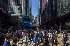 People cross a road in the Central district of Hong Kong, China, on Oct. 25, 2021.