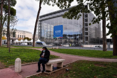 A woman checks her smartphone in a park opposite the convention center 