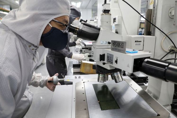 A worker inspects semiconductor chips at the chip packaging firm Unisem Berhad plant in Ipoh, Malaysia, on Oct. 15, 2021. 