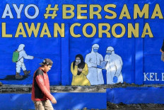 Living example: A man with no mask walks past a mural depicting COVID-19 health protocols in Tebet, South Jakarta. 