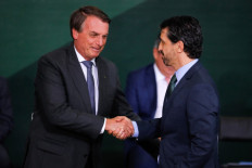 Brazil's President Jair Bolsonaro (L) shakes with Brazil's Environment Minister Joaquim Leite during the launching ceremony of the National Green Growth Program, at the Planalto Palace in Brasilia, on October 25, 2021.