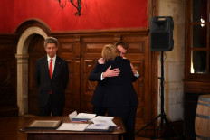 France's President Emmanuel Macron (center) congratulates outgoing German Chancellor Angela Merkel (right), flanked by her husband Joachim Sauer (left) during the ceremony of the Grand Cross, the highest distinction of the Legion d'Honneur, France's chief honour, in Beaune, Eastern France, on November 3, 2021. Macron hosted on November 3, 2021 outgoing Chancellor Angela Merkel for a valedictory visit as she bows out after 16 years in power, with the German leader cheered by crowds and awarded France's highest honour. 