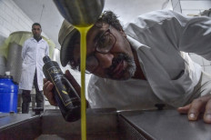 Algerian olive oil producer Hakim Alileche inspects a dripping batch at the press in Ain Oussera in the Djelfa province, south of the Algerian capital, on October 30, 2021.
