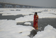 A devotee takes a dip in the waters of Yamuna river as a part of rituals for the upcoming Hindu festival of Chhat puja amid foam created by pollution in the water in New Delhi on November 8, 2021.