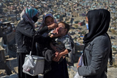A health worker (L) administers polio vaccine drops to a child during a vaccination campaign in the old quarters of Kabul on November 8, 2021.