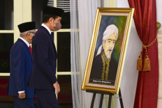 President Joko "Jokowi" Widodo (center) and Vice President Ma'ruf Amin pass by a framed portrait of Raden Aria Wangsakara, an Islamic scholar from Banten from the 1600s, ahead of the inauguration ceremony for national heroes at the State Palace in Jakarta, on Nov. 10, 2021. Wangsakara, who also happens to be an ancestor of Ma'ruf, was posthumously given the title of national hero on Heroes Day.