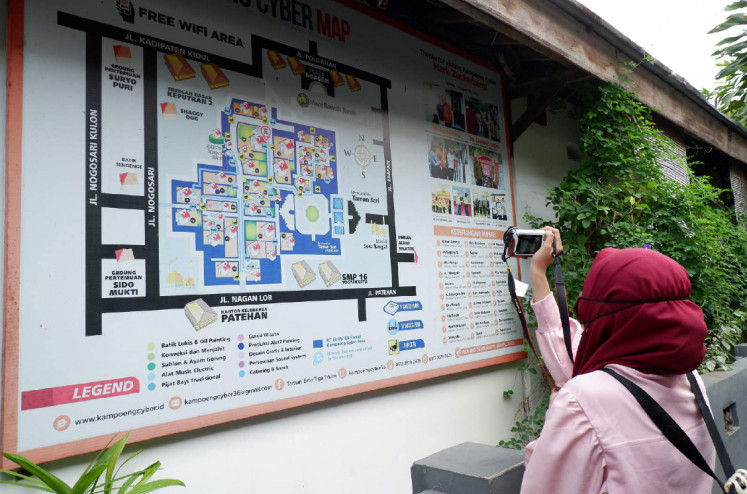 Interconnected: A visitor takes a photo of the village's map, which shows every key locations, including the businesees there. (JP/A. Kurniawan Ulung)