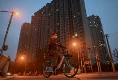 A man pedals a bike past a housing complex built by Chinese property developer Evergrande in Beijing on October 25, 2021.