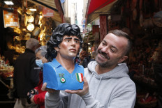 A man holds a figure by Gennaro Di Virgilio depicting late Argentinian football legend Diego Armando Maradona in Via San Gregorio Armeno, the street of the Christmas cribs craftmen in Naples on November 23, 2021.