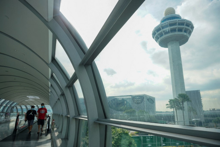 People walk along the link bridge to a terminal at Changi International Airport in Singapore on November 18, 2021. 