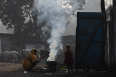 In this file photo taken on November 18, 2021, a woman along with her child burns coal for domestic use at Singrauli in India's Madhya Pradesh state.